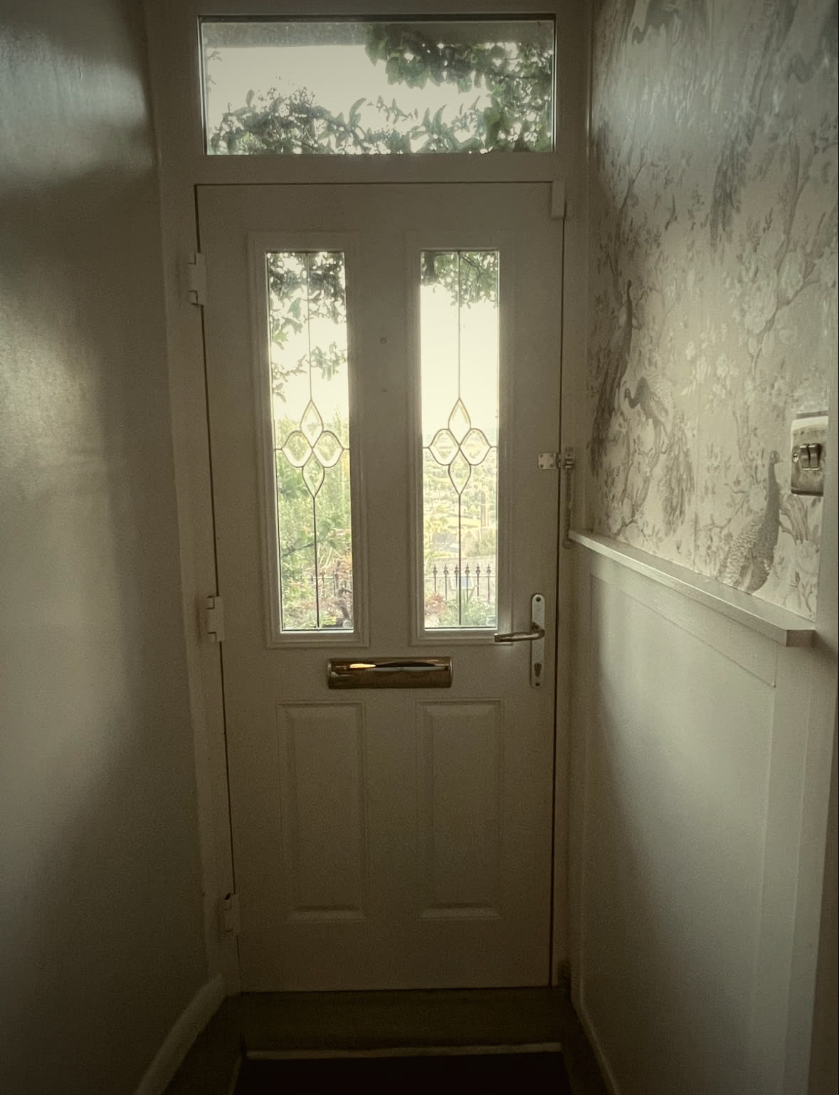 Entrance hall with fitted wall panelling, patterned wallpaper and a glazed front door