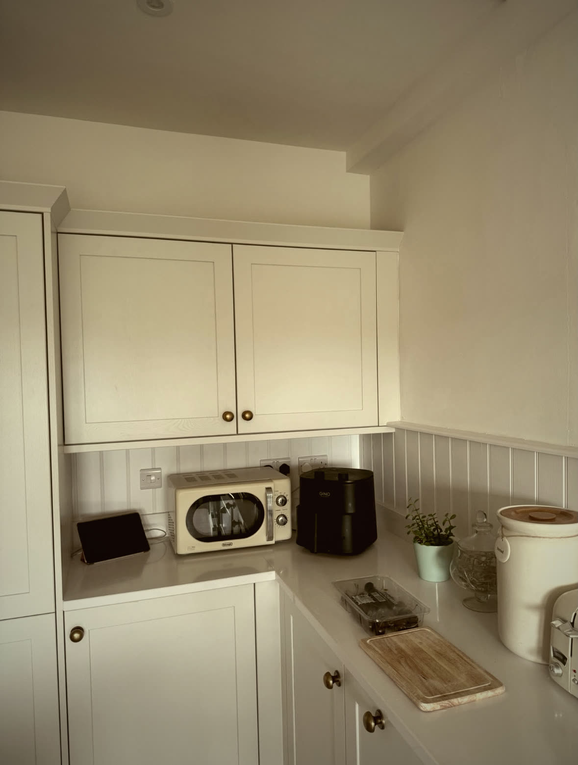 Kitchen corner with wall cabinets, tongue-and-groove panelled splashback and quartz worktop