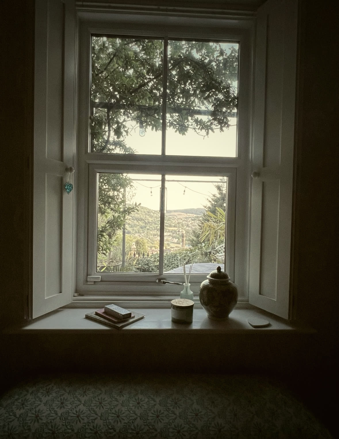 Restored sash window with panelled shutters and a built-in window seat looking out over the valley